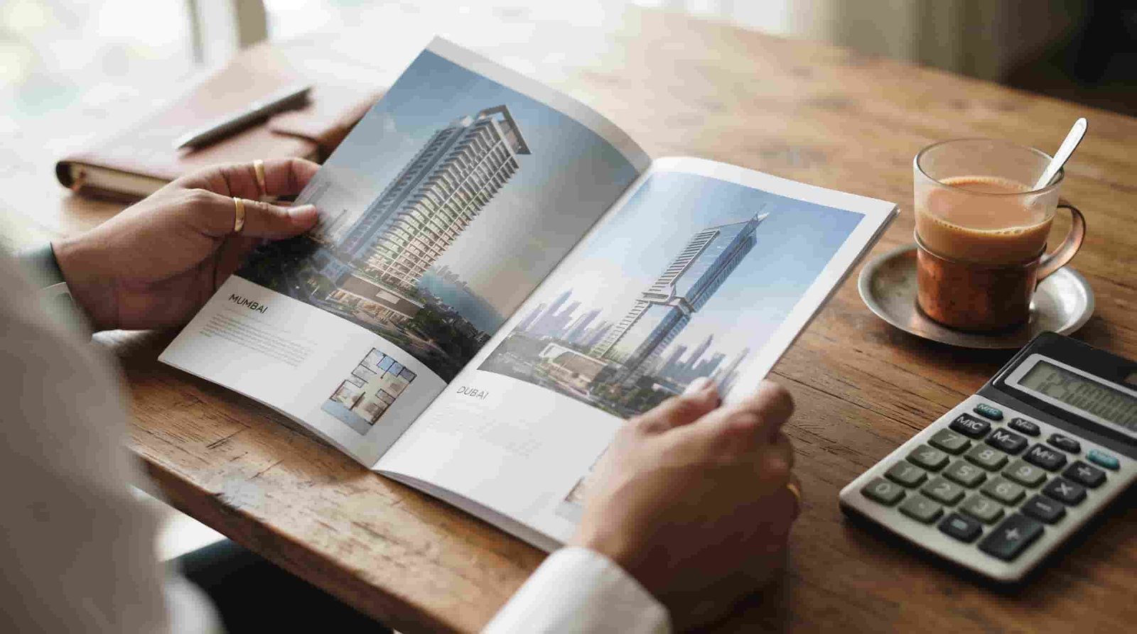 Investor comparing Dubai and Mumbai apartment prices on a desk